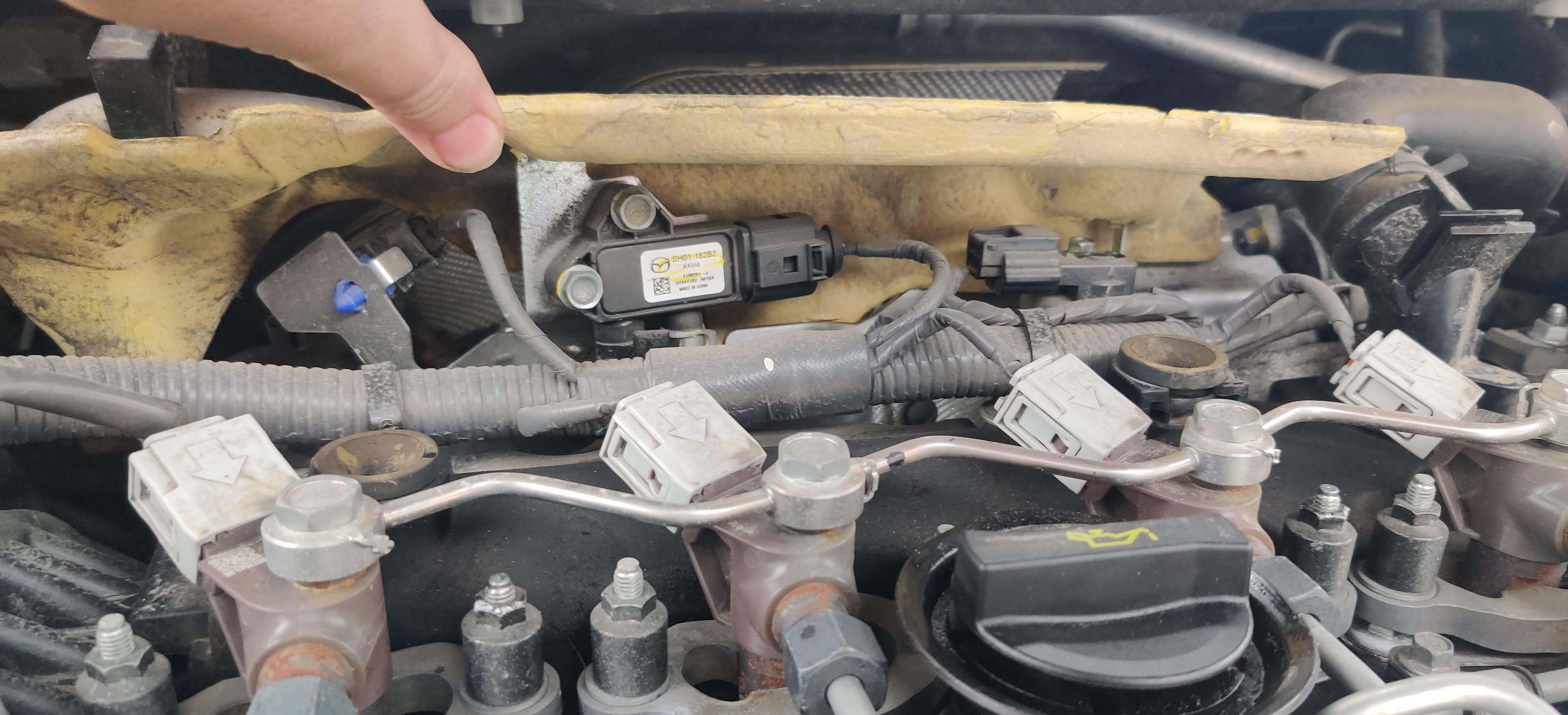 Hand pointing to a sensor in a diesel van engine bay during a diagnostic pre-check