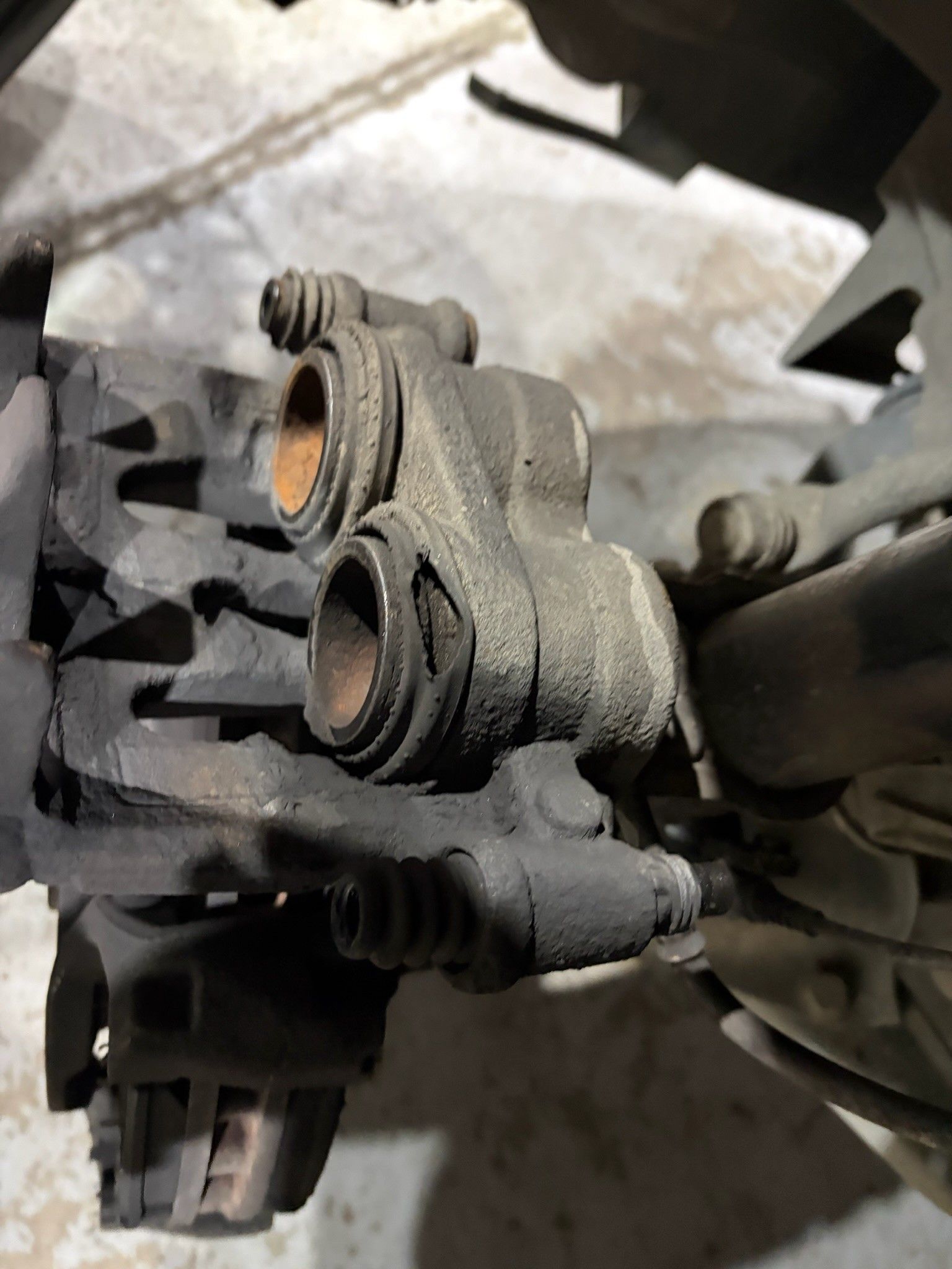 Worn brake caliper with torn dust boot and rusty pistons