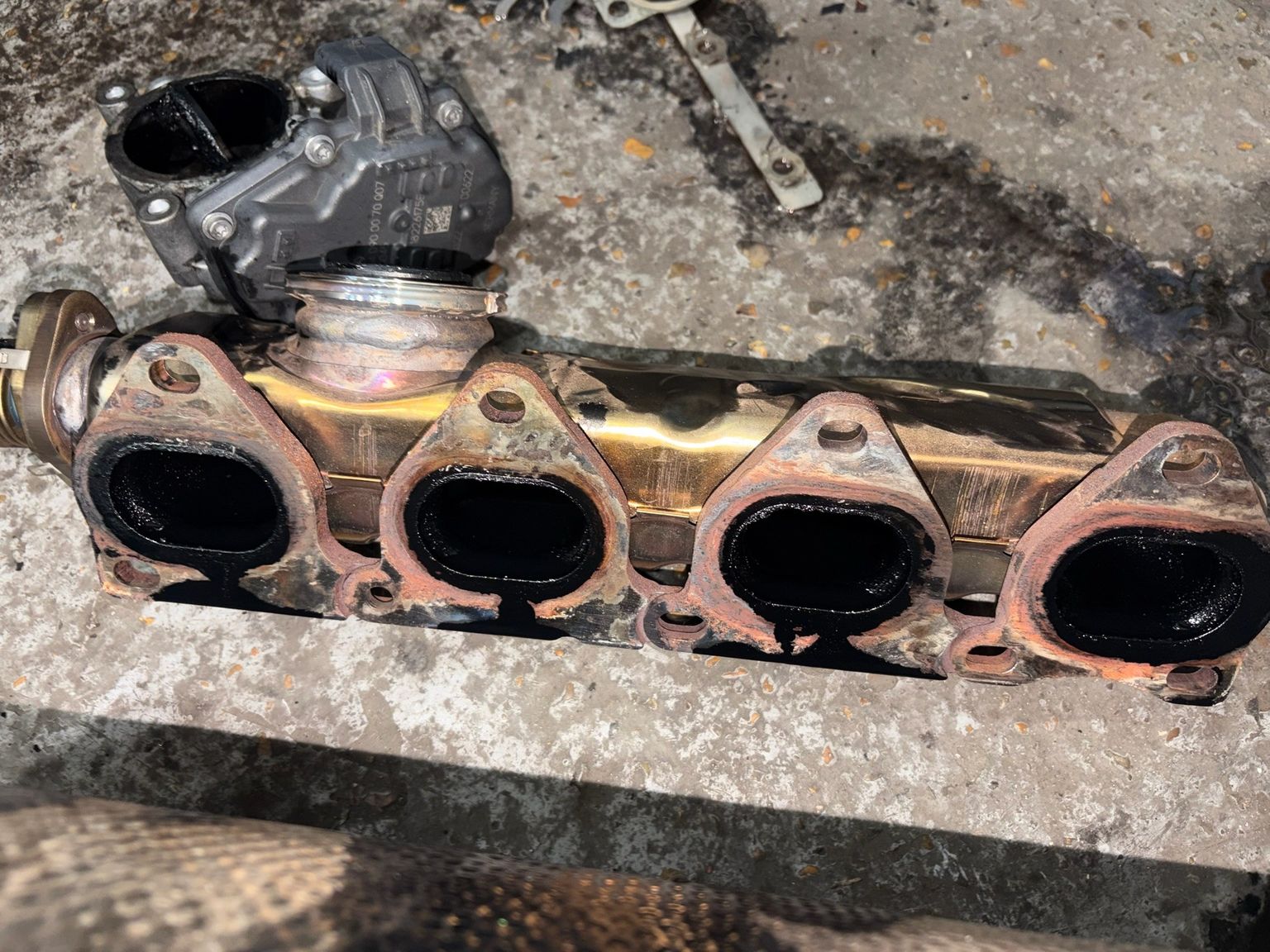 Removed intake manifold and throttle body with carbon deposits on workshop floor