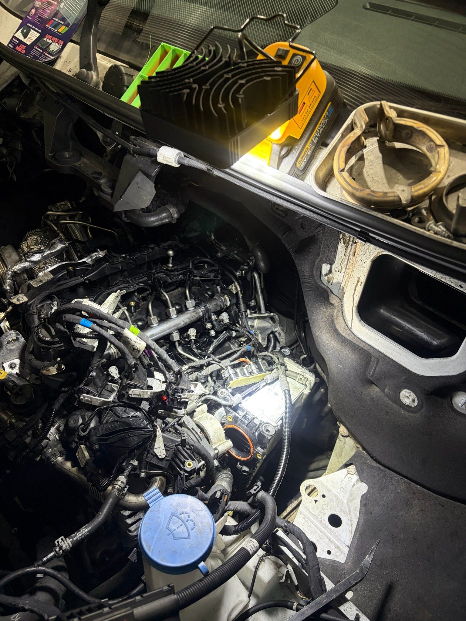 Sprinter engine bay lit by DeWalt work light during injector repair