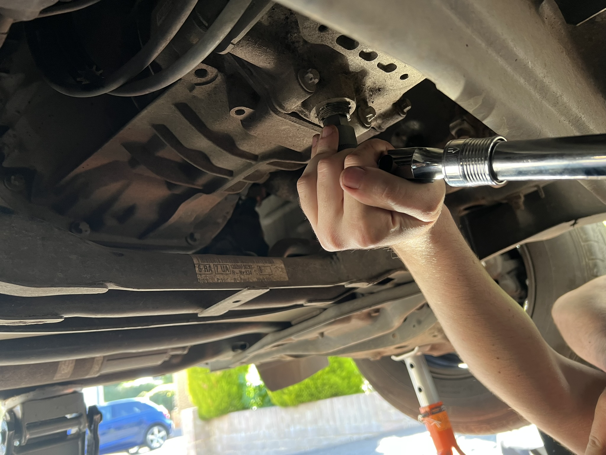Sump drain plug being loosened during an oil change