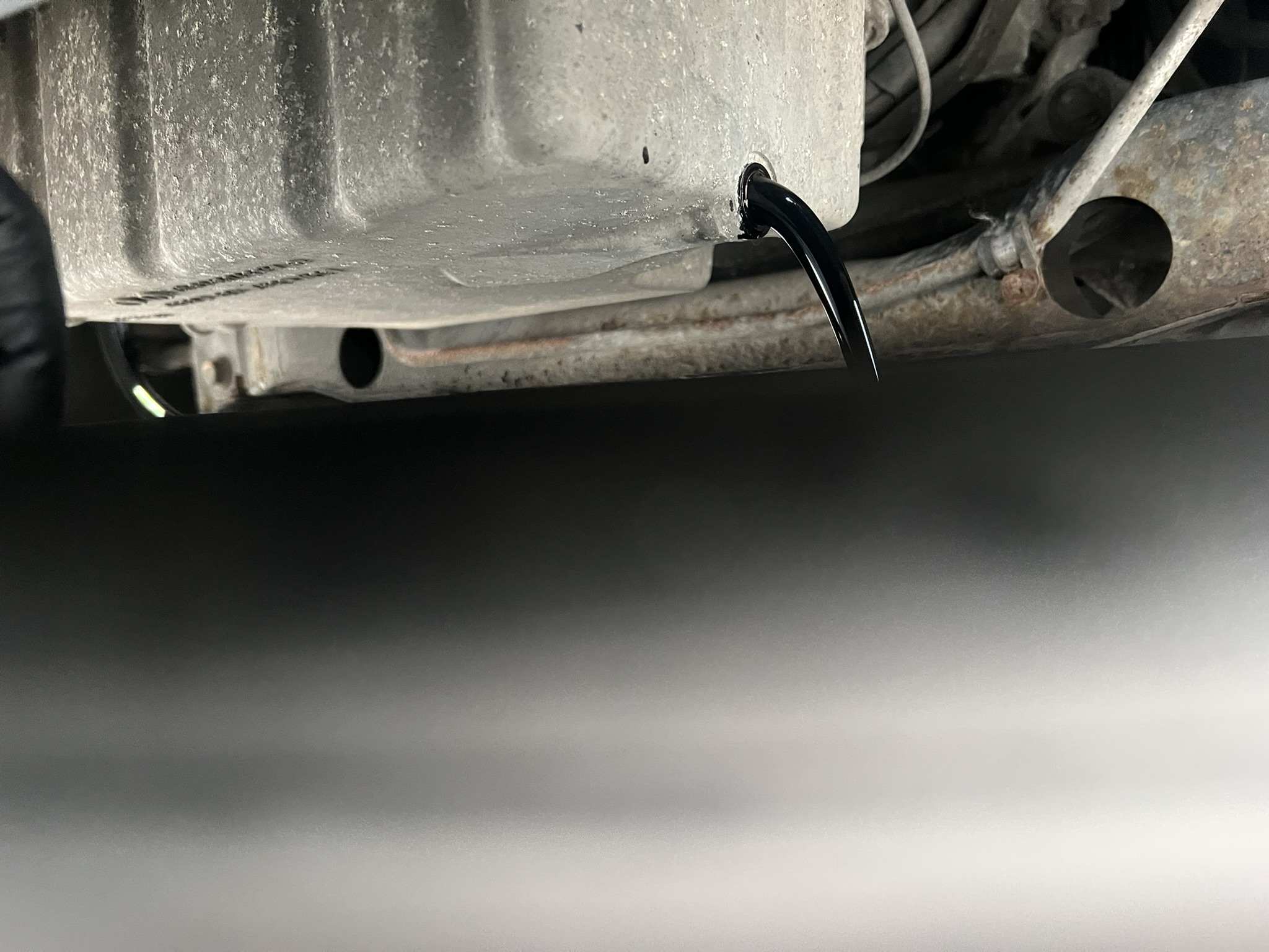 Old engine oil draining from sump during service