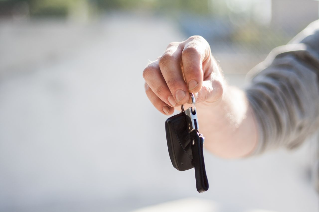 A hand holding out the keys to a used car